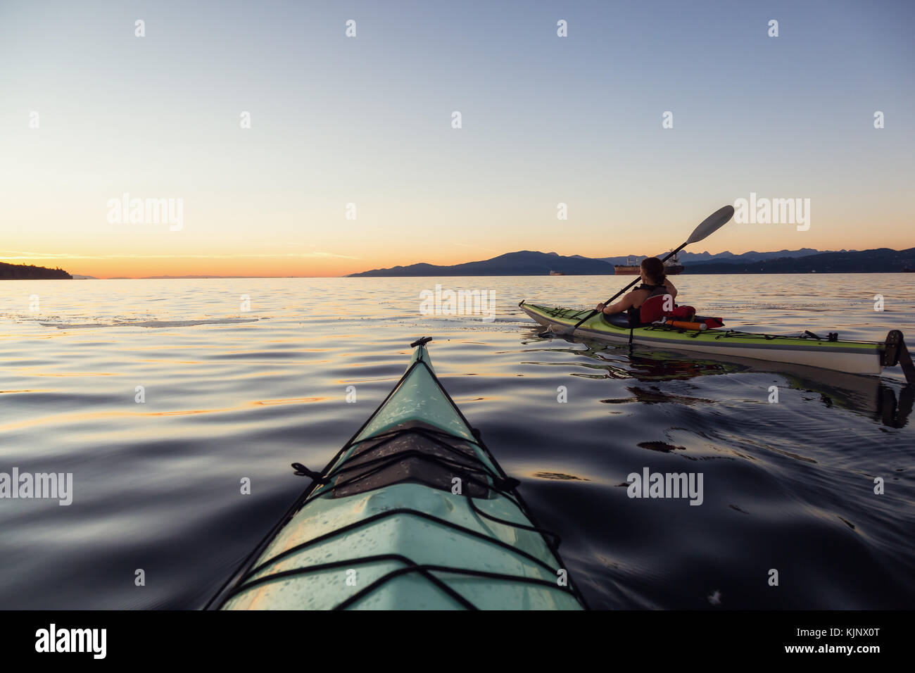 Sea kayaking in the ocean during a colorful and vibrant sunset. Taken ...