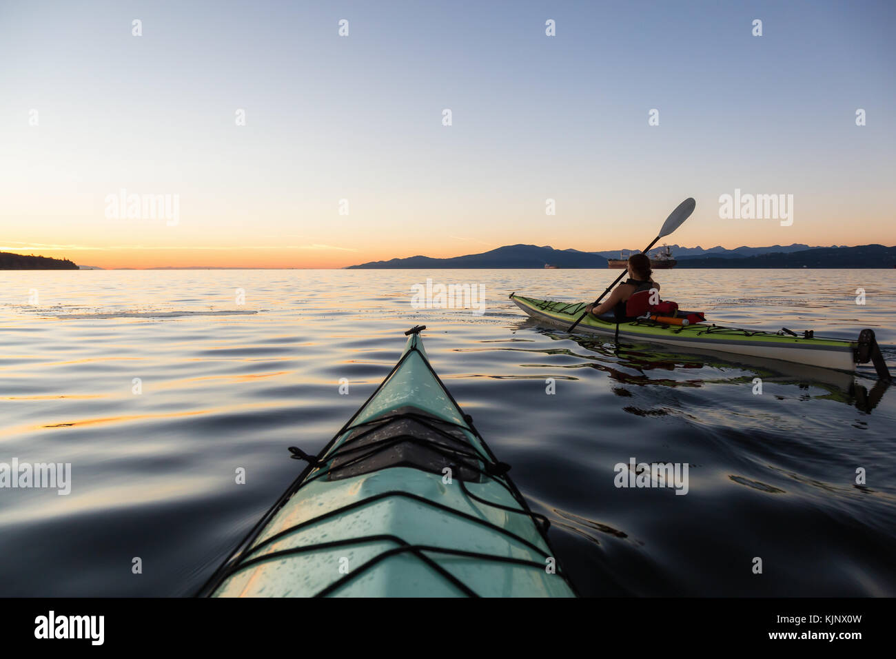 Sea kayaking in the ocean during a colorful and vibrant sunset. Taken