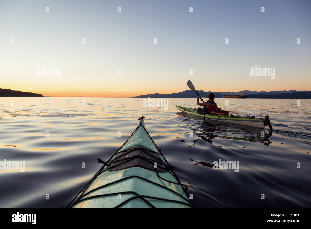 Sea kayaking in the ocean during a colorful and vibrant sunset. Taken ...