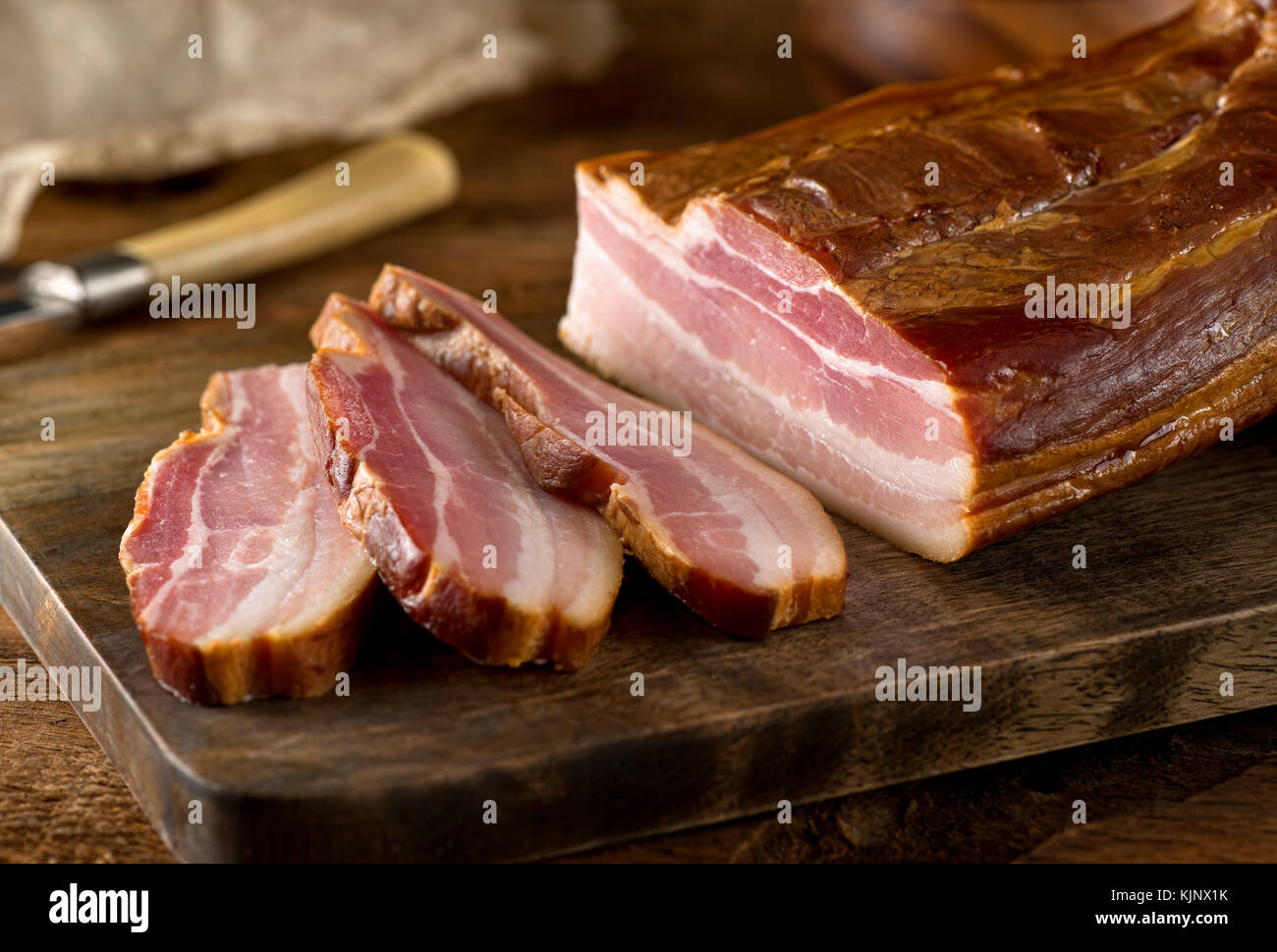Delicious artisanal whole smoked slab bacon on a cutting block. Stock Photo