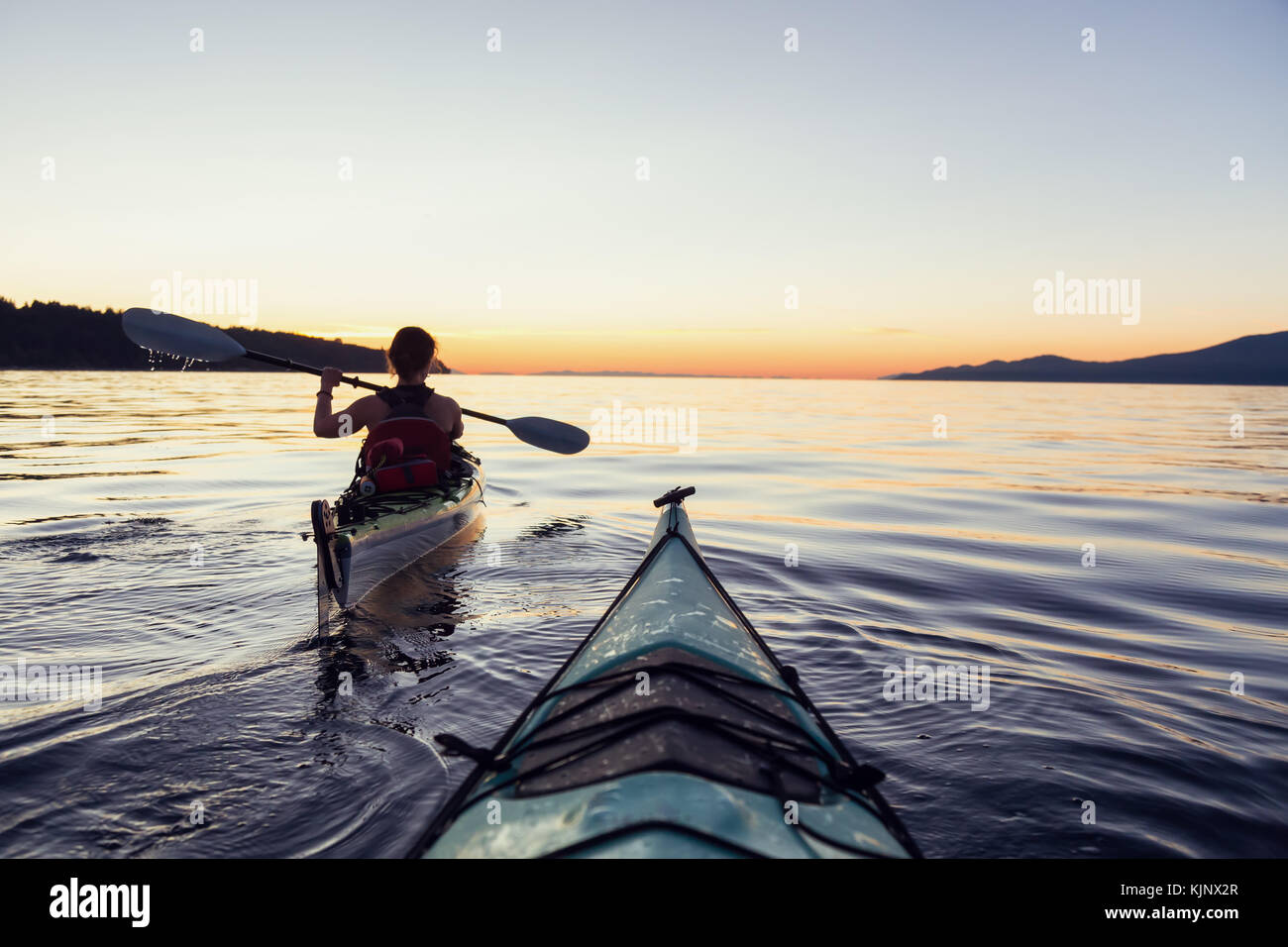 Sea kayaking in the ocean during a colorful and vibrant sunset. Taken ...