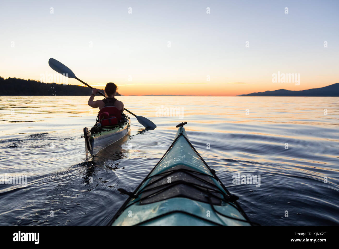 Sea kayaking in the ocean during a colorful and vibrant sunset. Taken