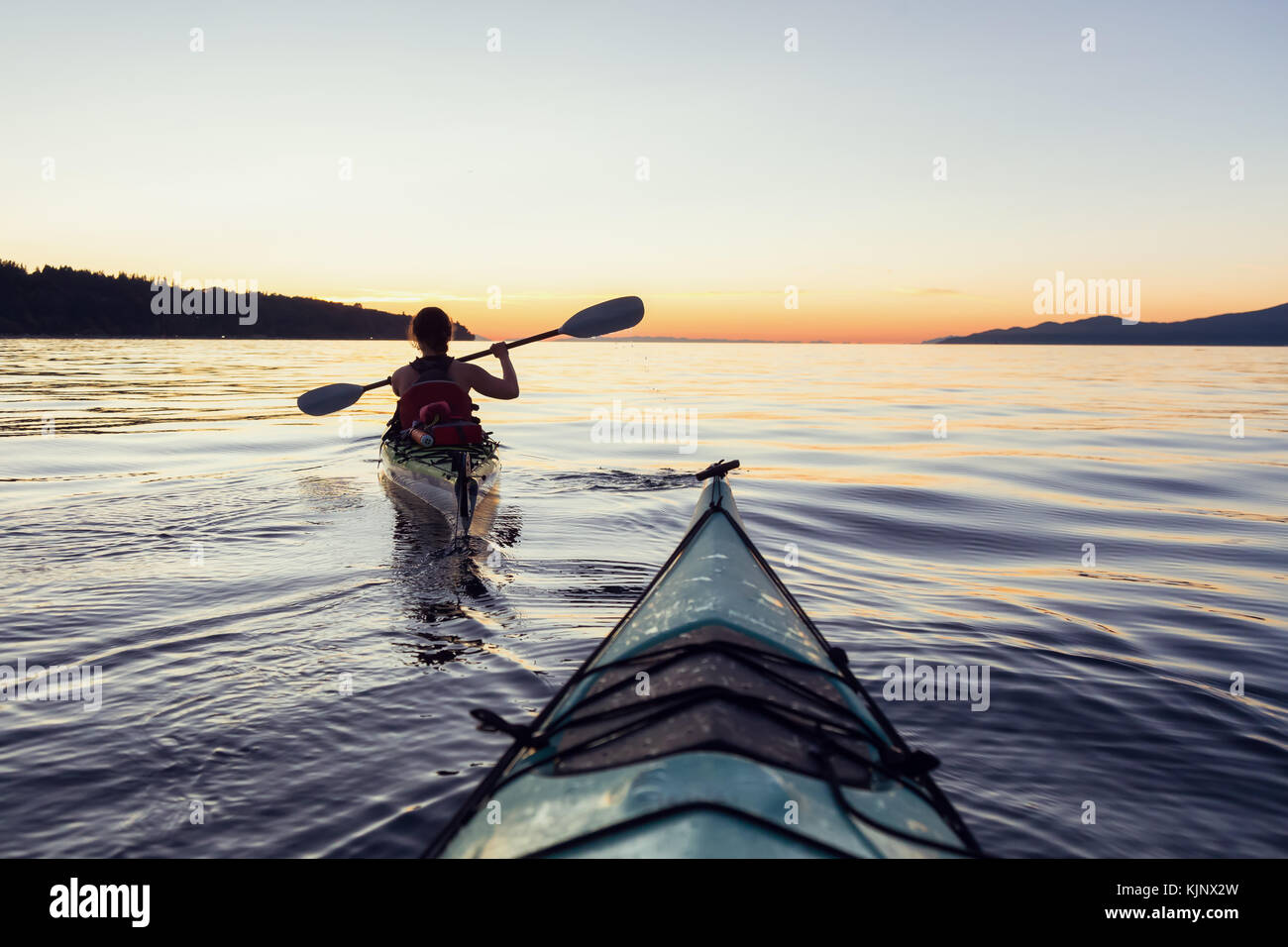 Sea kayaking in the ocean during a colorful and vibrant sunset. Taken