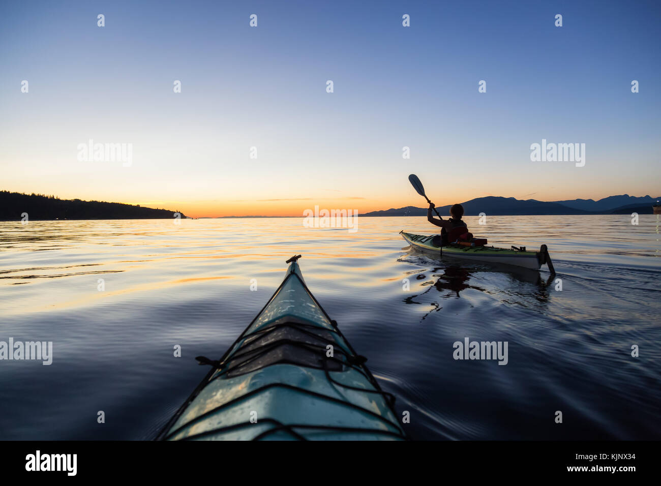 Sea kayaking in the ocean during a colorful and vibrant sunset. Taken
