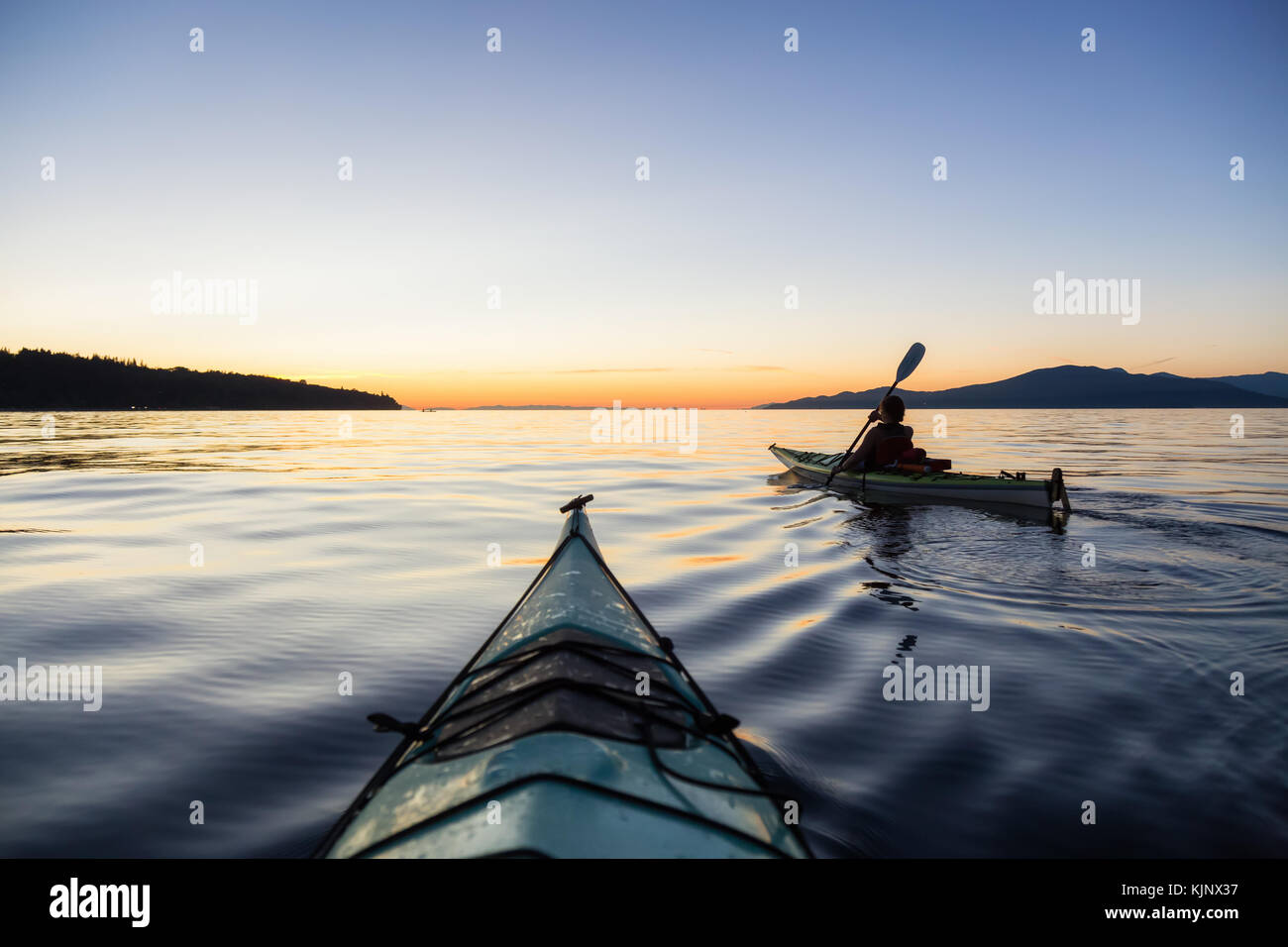 Sea kayaking in the ocean during a colorful and vibrant sunset. Taken ...