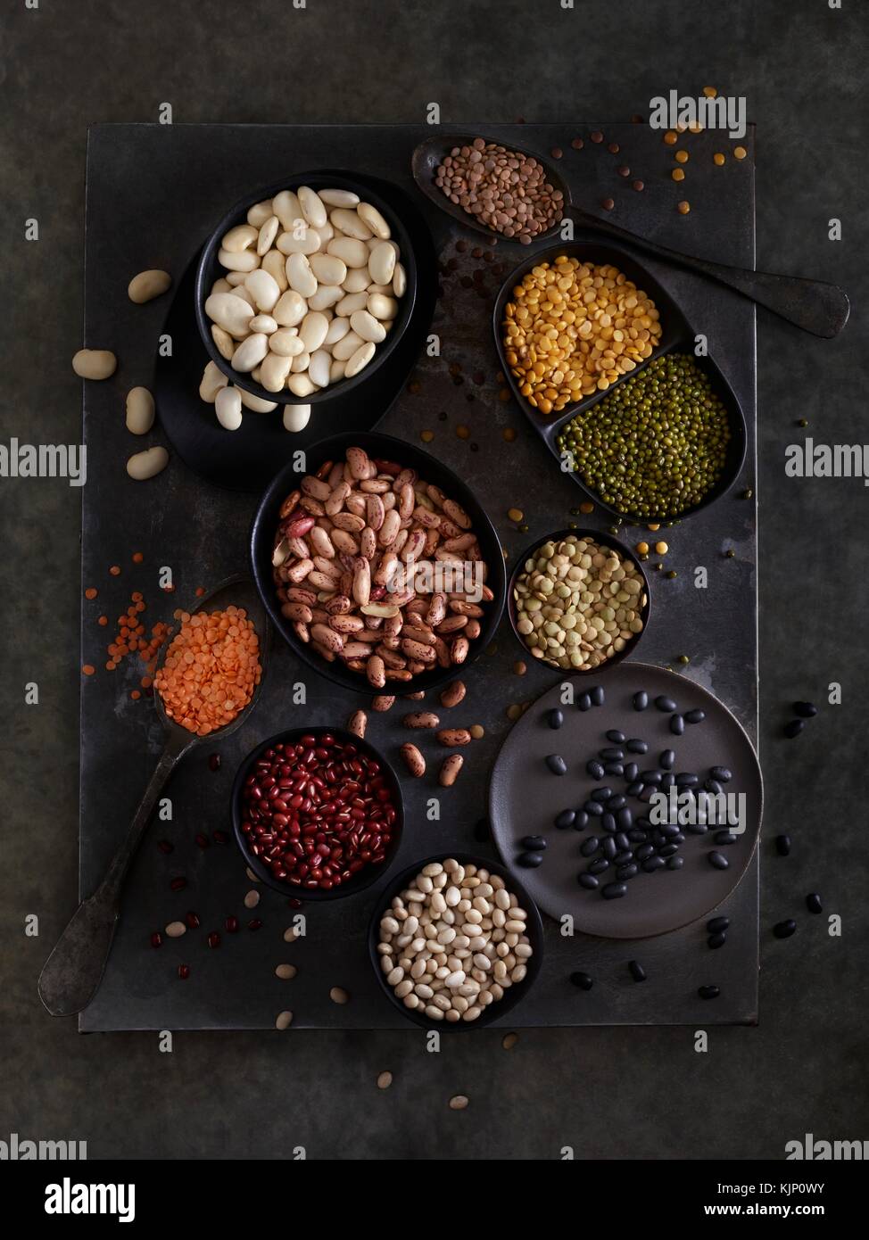 Pulses in bowls against dark background, overhead view. Stock Photo