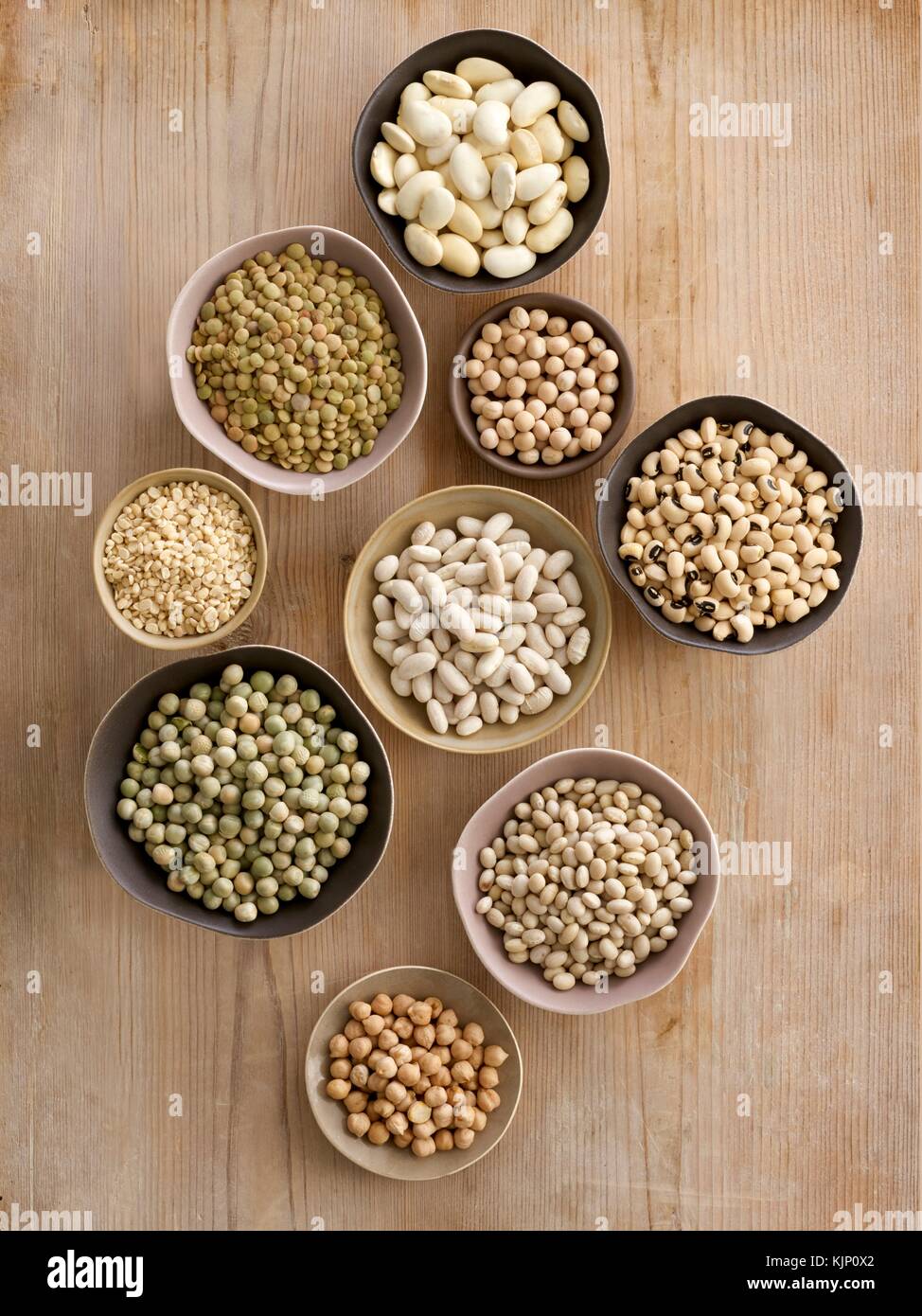 Pulses in bowls on a chopping board, overhead view. Stock Photo