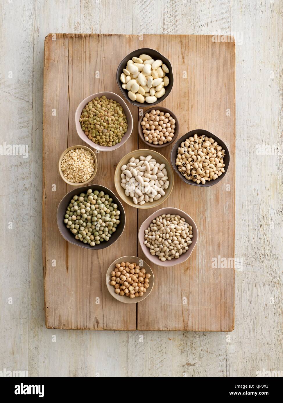Pulses in bowls on a chopping board, overhead view. Stock Photo