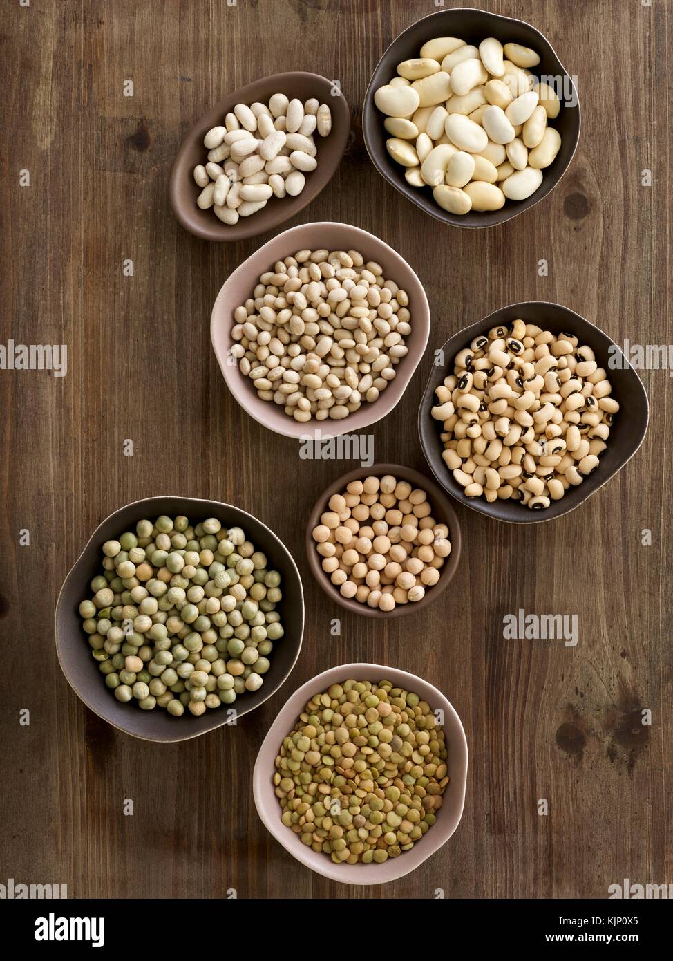 Pulses in bowls on a chopping board, overhead view. Stock Photo