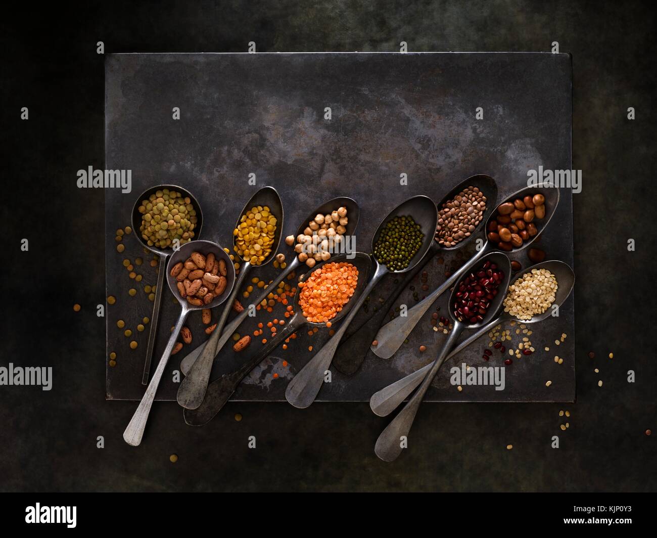 Pulses on metal spoons, overhead view. Stock Photo