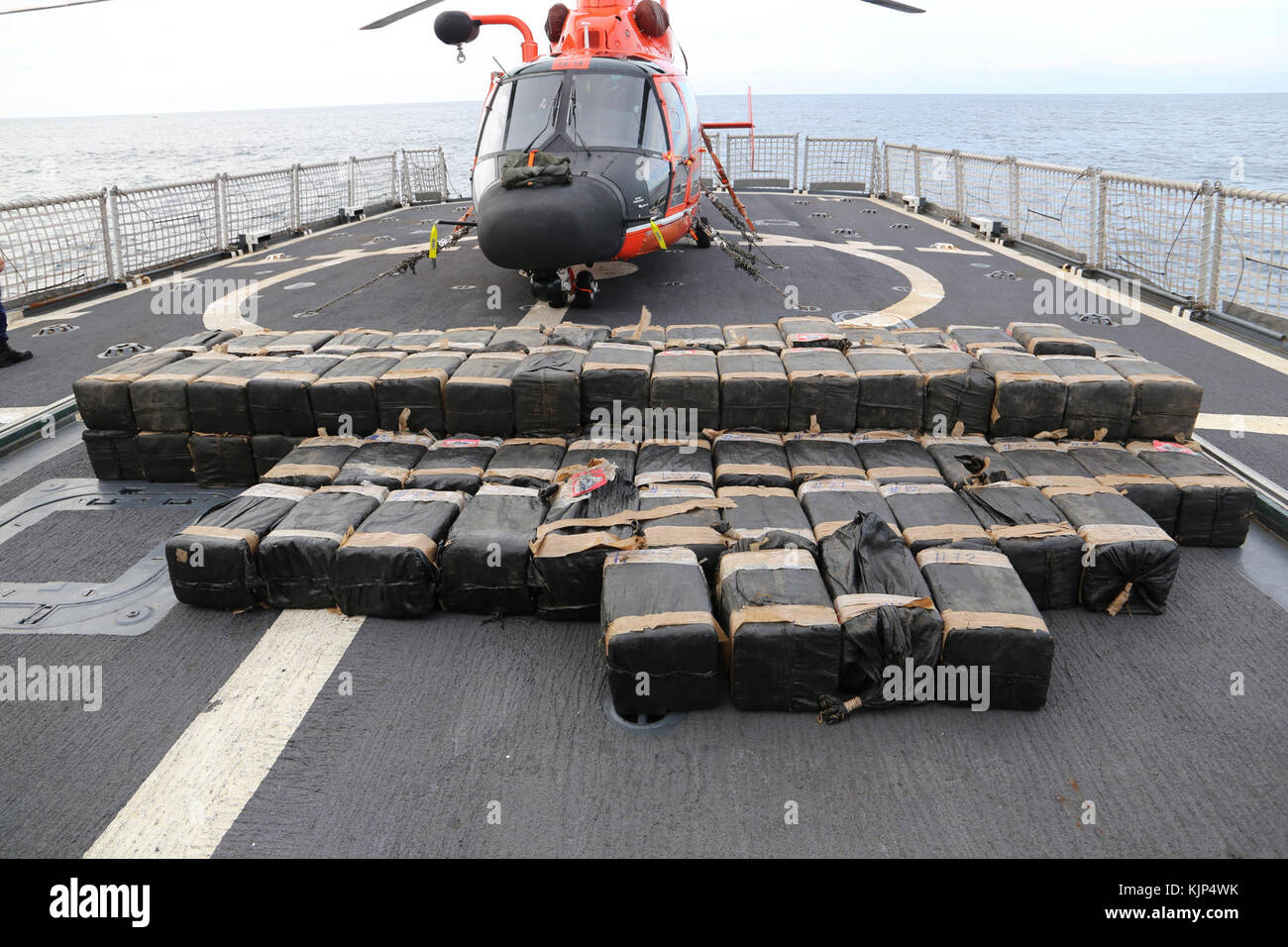 Over 2200 kilograms of seized contraband lie on Coast Guard Cutter Spencer’s flight deck with an MH-65 Dolphin Helicopter from Jacksonville, FL. The fight against transnational organized crime networks in the Eastern Pacific requires unity of effort in all phases from detection, monitoring and interdiction, to prosecution. Coast Guard photo by Petty Officer Second Class Timothy Midas. Stock Photo