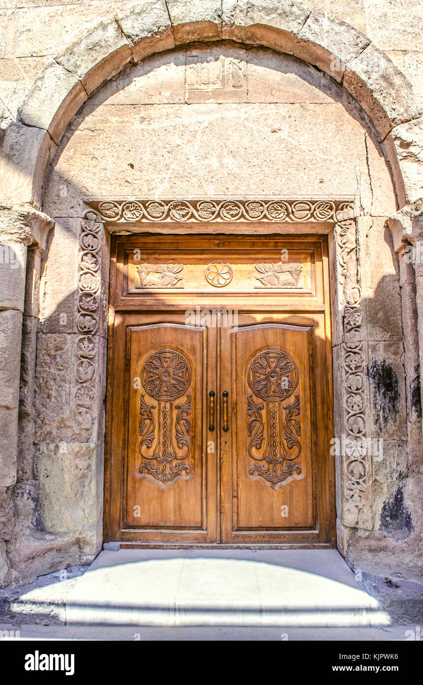 Arched central entrance at monastery Odzun with  bivalve wooden the entrance door covered carved patterns Stock Photo