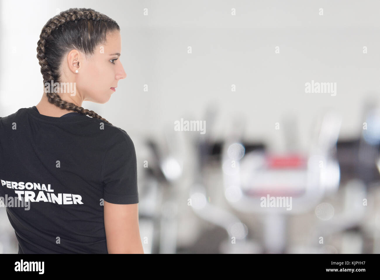 Female Personal Trainer, with her back facing the camera in a gym Stock Photo