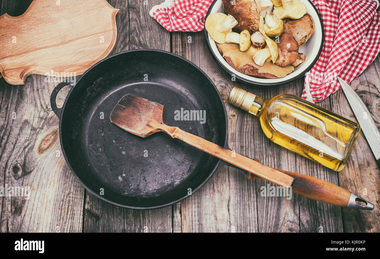 fresh edible wild mushrooms, olive oil and black round cast-iron frying pan, top view Stock Photo
