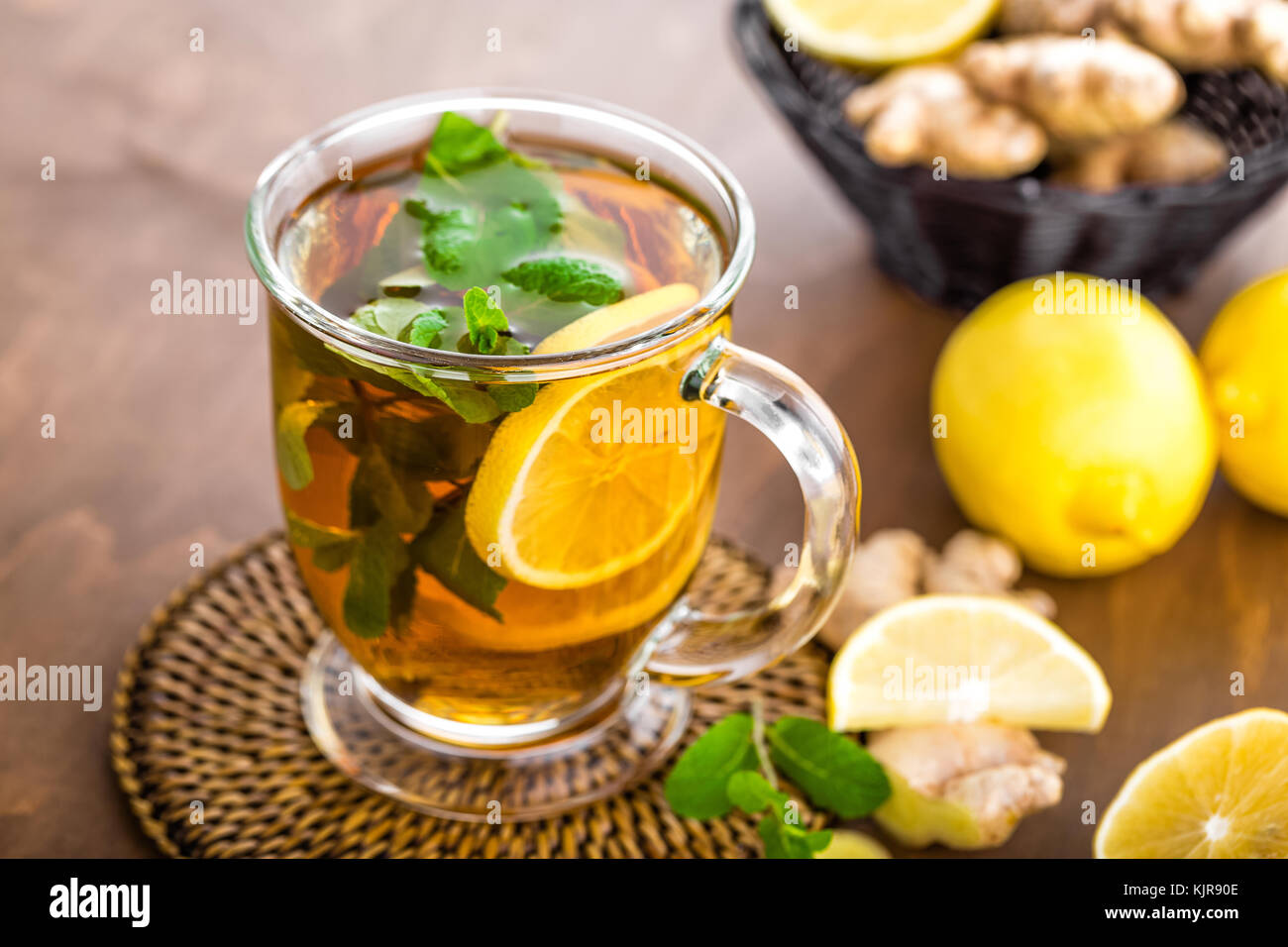 Hot herbal tea with fresh lemon, ginger and mint leaves on brown ...