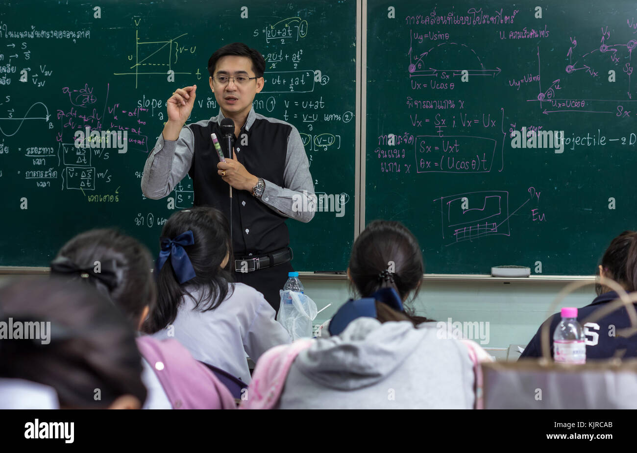 Asian teacher Giving Lesson to group of College Students which answer the  question in the classroom over the physics formular in thai laguage on  black Stock Photo - Alamy