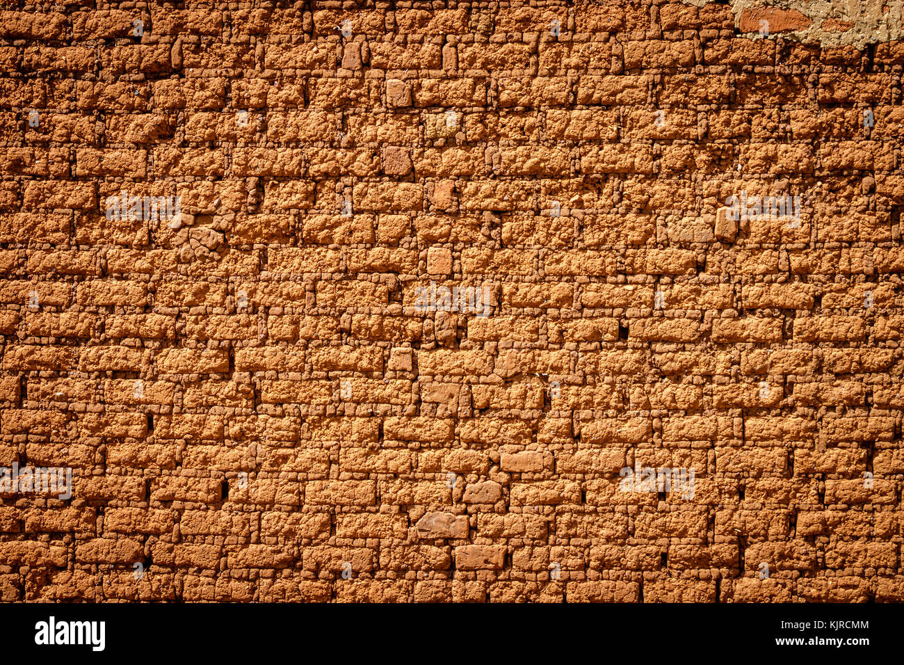 A typical mud brick wall of a house in Uganda. A brick is building material used to make walls, pavements and other elements in masonry construction. Stock Photo