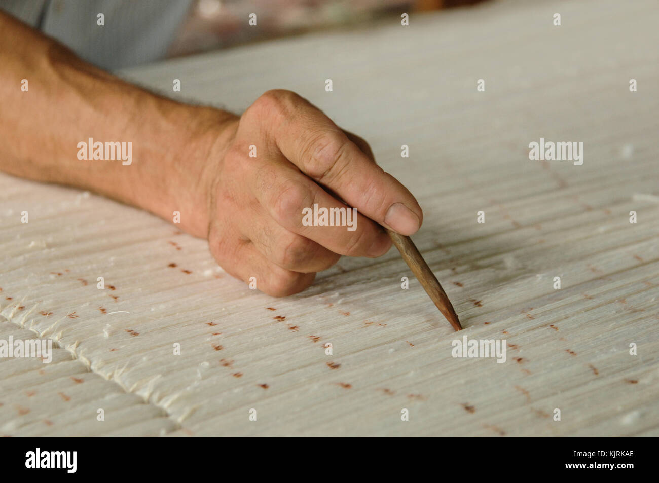 hand with a pencil makes marks on the carpet. weaving and manufacturing