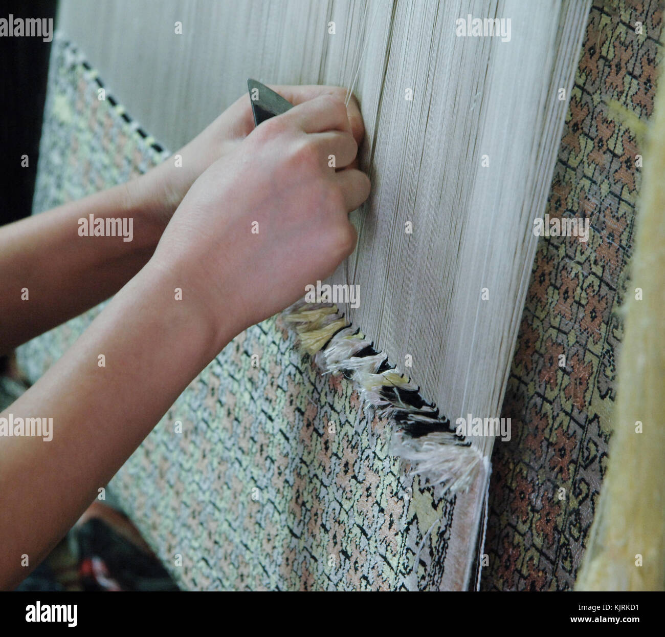 weaving and manufacturing of handmade carpets closeup. women's hands weave a carpet Stock Photo