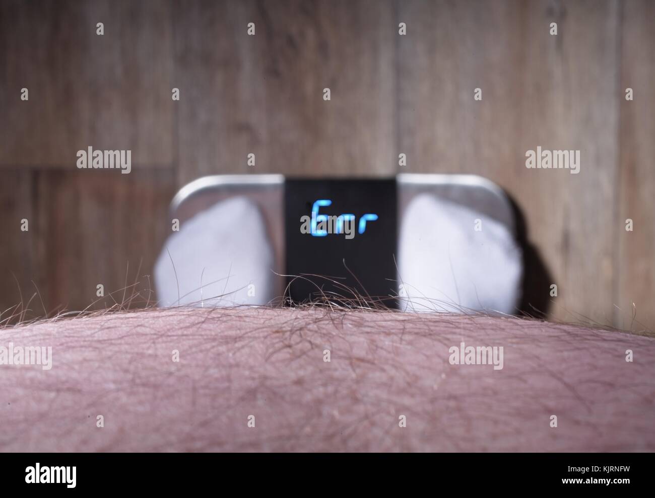 Overweight man looks at a error sign of a weighting scale Stock Photo