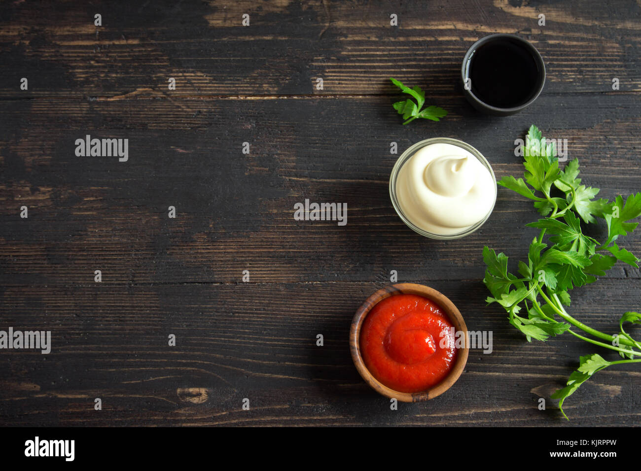 Ketchup, mayonnaise and soy sauce assorted sauces on on dark wooden