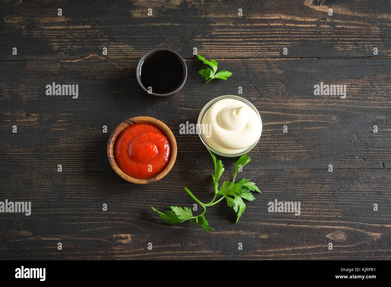 Ketchup, mayonnaise and soy sauce assorted sauces on on dark wooden background, copy space