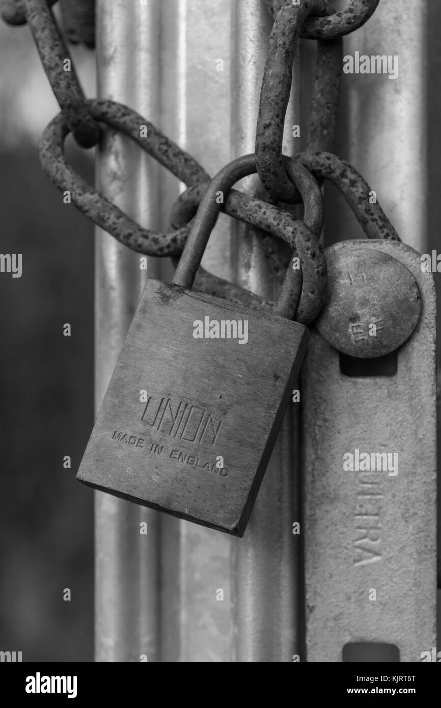 Black & white of padlock & chain securing industrial gate. For email data security, secure online payments & login, industrial decline, Covid lockdown Stock Photo