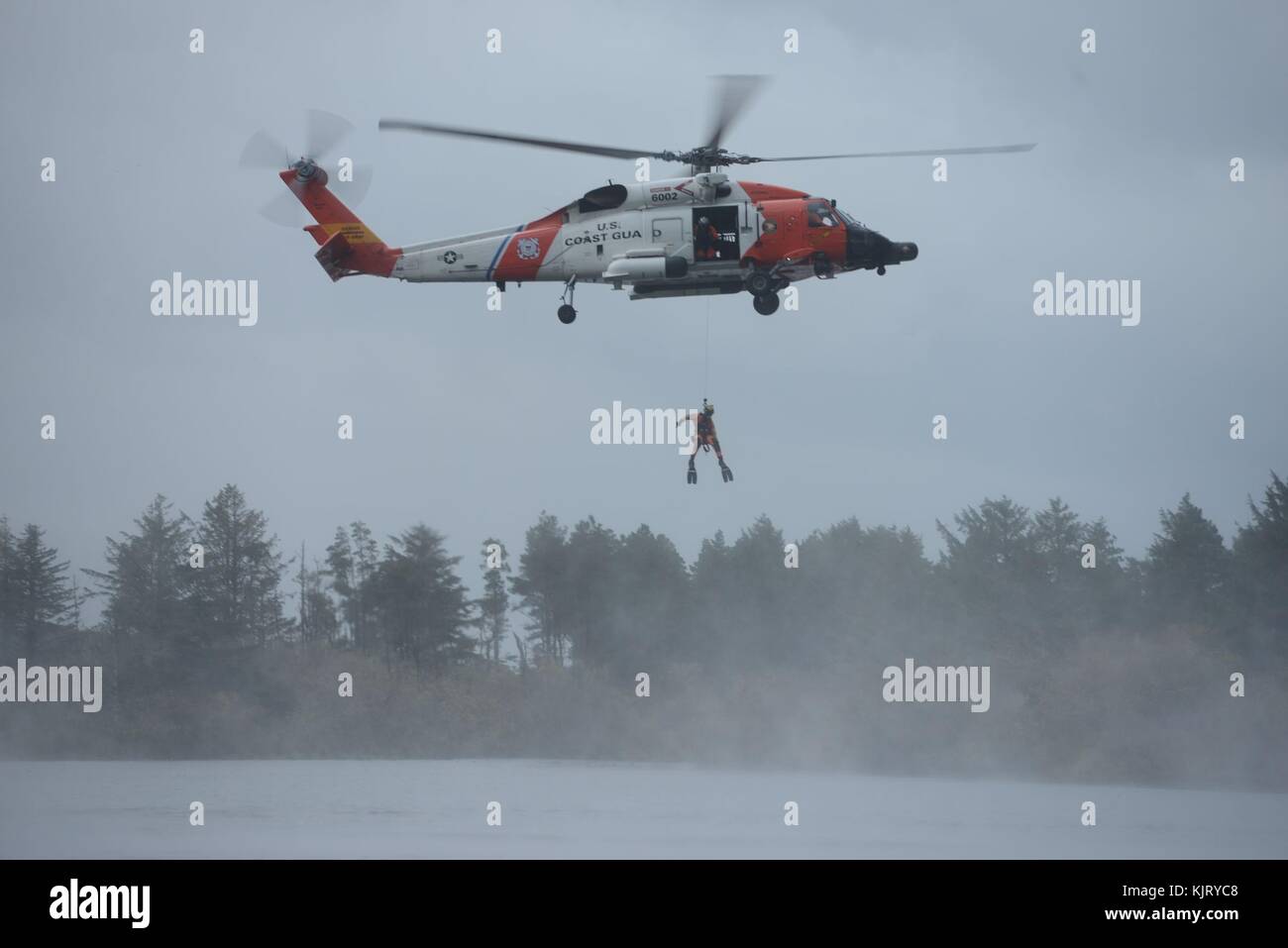 A U.S. Coast Guard officer is lowered from a MH-60 Jayhawk helicopter during a search and rescue demonstration for the U.S. China Disaster Management Exchange exercise at Camp Rilea November 16, 2017 in Warrenton, Oregon.  (photo by Levi Read via Planetpix) Stock Photo