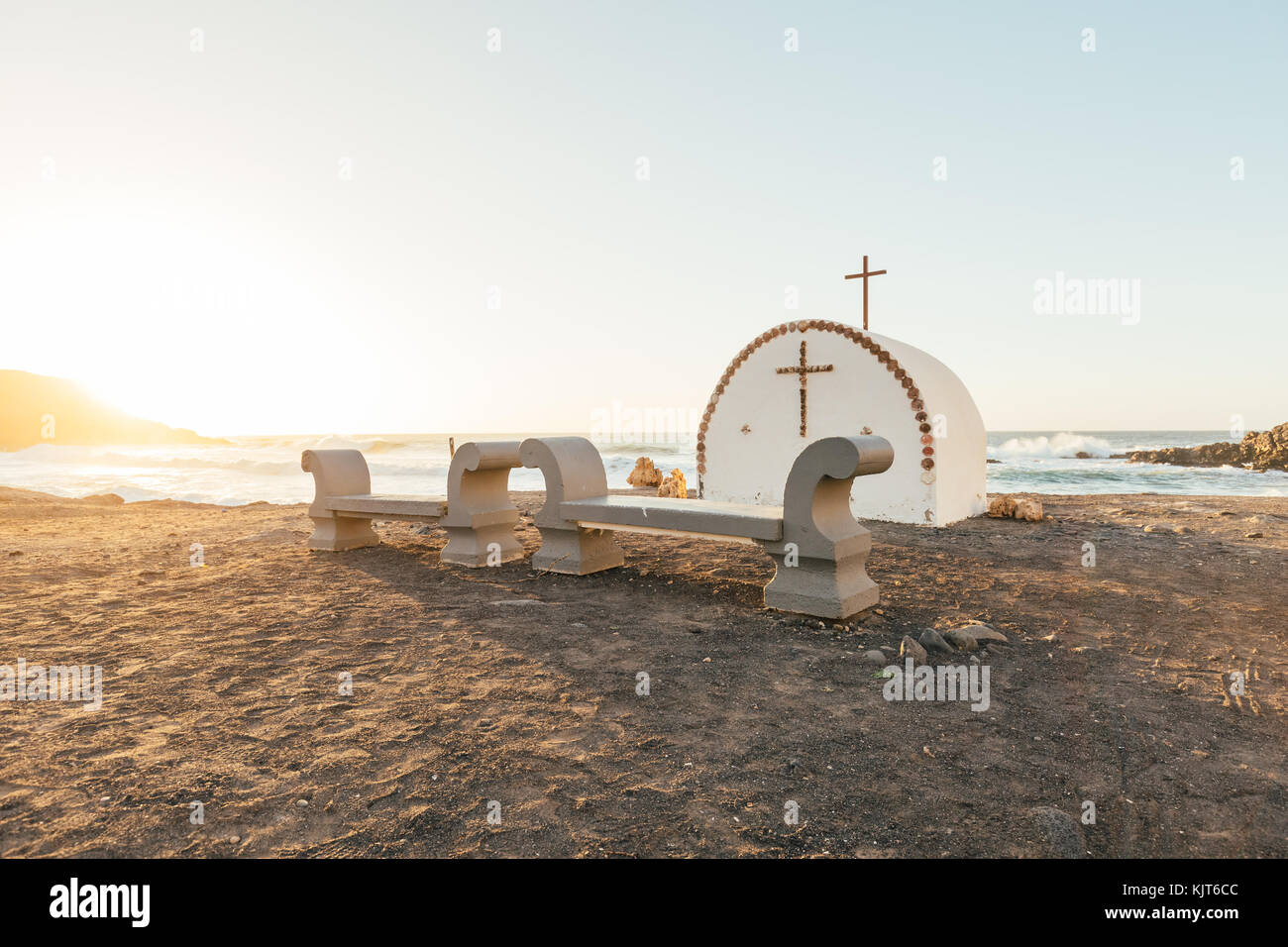 A little chapel with a cross and benches at the coast of Fuerteventura (Spain) at dusk Stock Photo