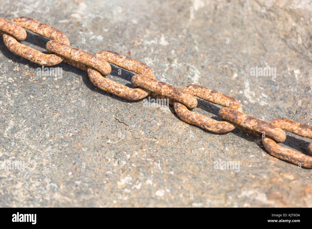 A closeup of a rusty chain on a rock Stock Photo