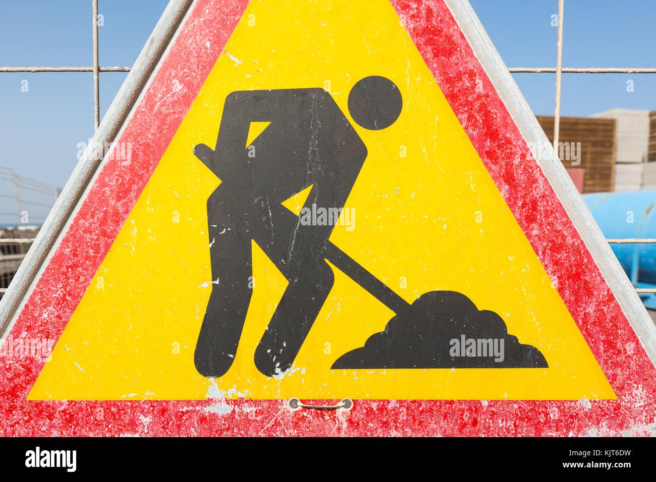 A triangle warning sign on a fence at a construction site symbolizing a digging worker Stock Photo