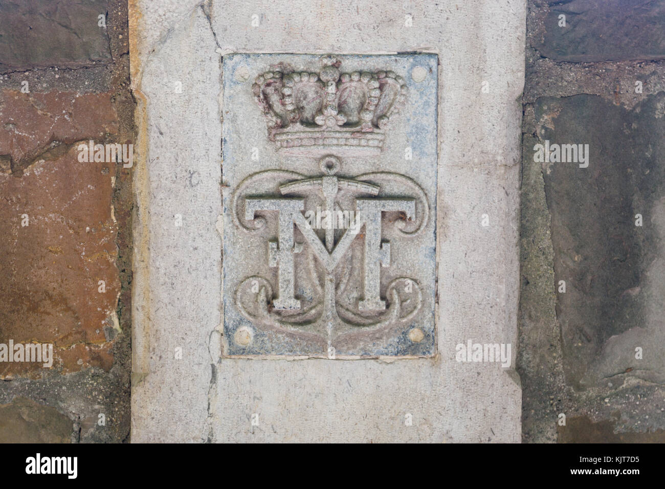 Initials of Mexican Emperor Maximilian and symbols crown and anchor on a stone wall at castle Miramare, Trieste, Italy Stock Photo