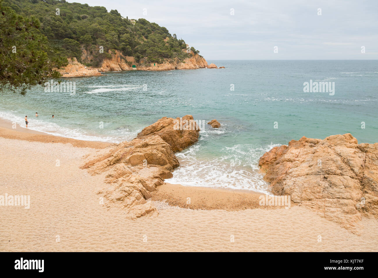 The bay and beach of Tamariu, Spain, with three swimmers Stock Photo