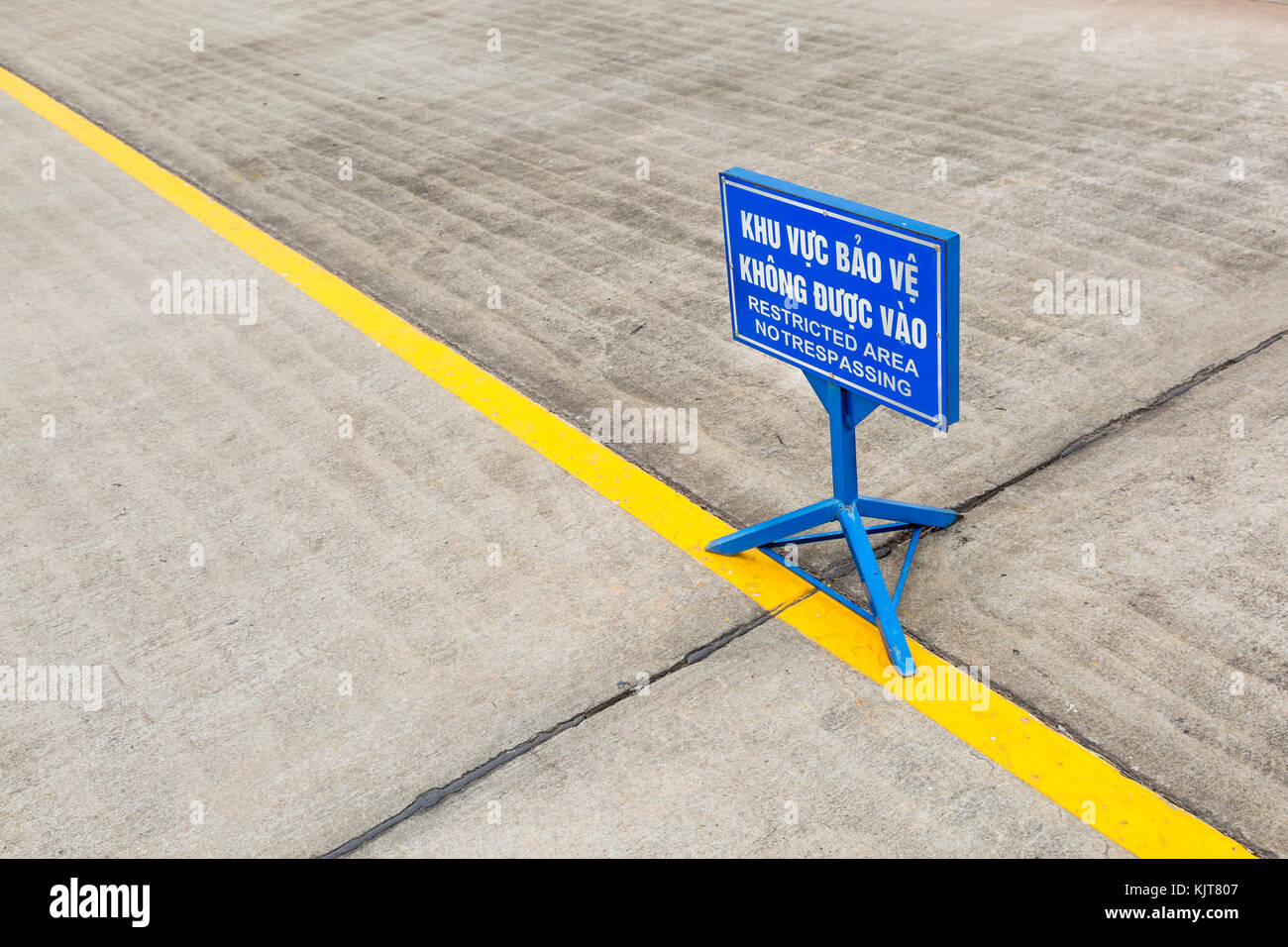 Blue sign for restricted area (no trespassing) in vietnamese and english behind a yellow line in front of the Ho Chi Minh mausoleum in Hanoi, Vietnam Stock Photo