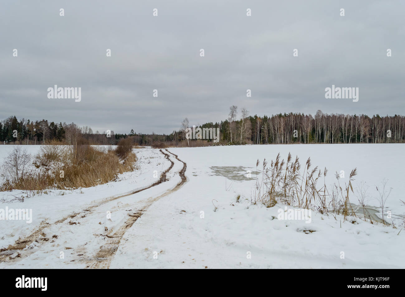 country road in winter with tyre tracks in the snow and ice Stock Photo ...