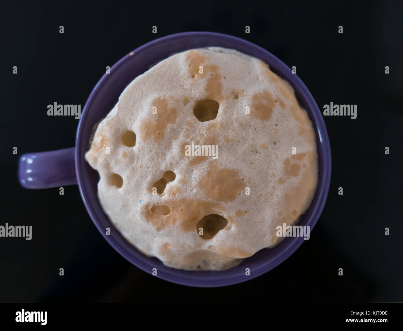 Close up of baker's yeast in a purple cup on black background. Stock Photo