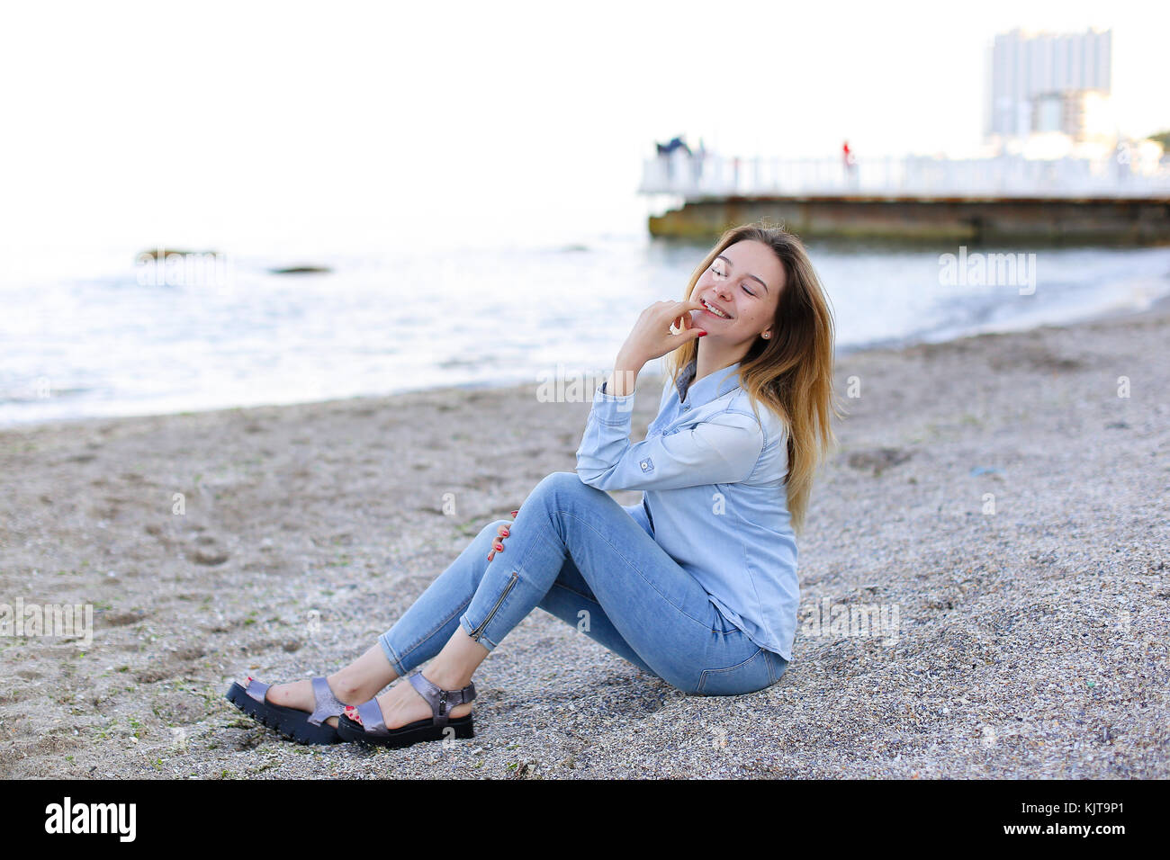 Smiling Young Woman Rests On Beach And Poses In Camera Sitting