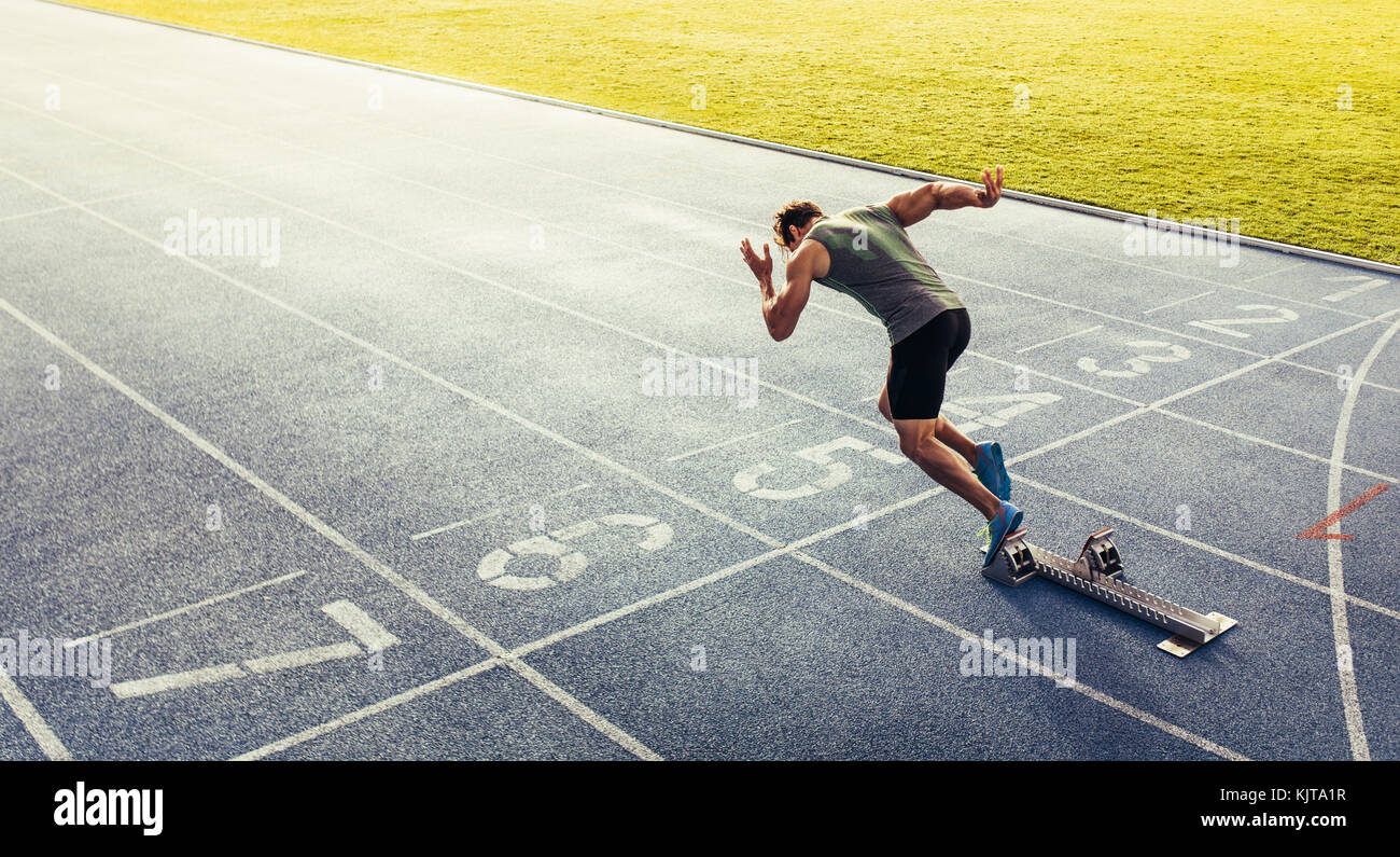 Running Track First Person Rear view of an athlete starting his sprint on an all-weather running ...