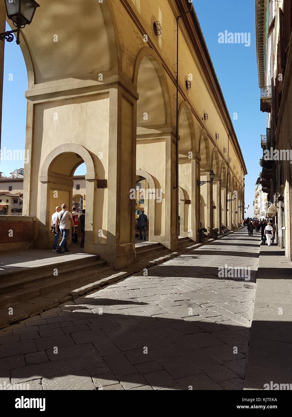 Tourists walking down the Lungarno degli Archibusieri avenue on a bright afternoon leading to Ponte Vechhio, Florence, Tuscany, Italy 2016 Stock Photo