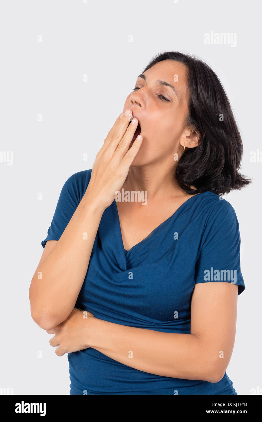 A latin woman yawning, wearing blue blouse and black hair Stock Photo