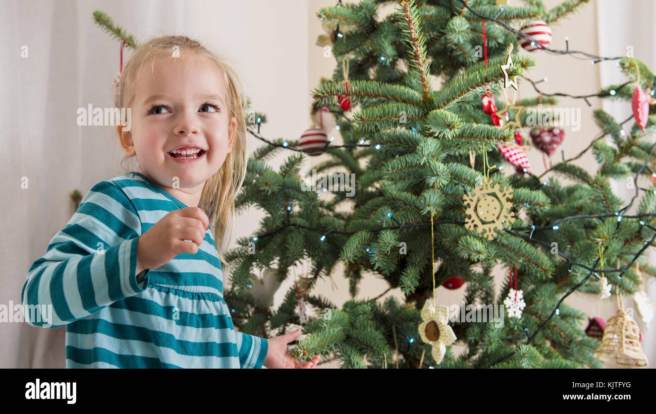 Cute blond preschool girl decorating christmas tree. Authentic family xmas time concept Stock Photo