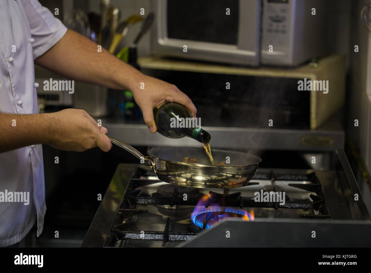 Chef cooking food in flambe style over a gas stove. Natural light and