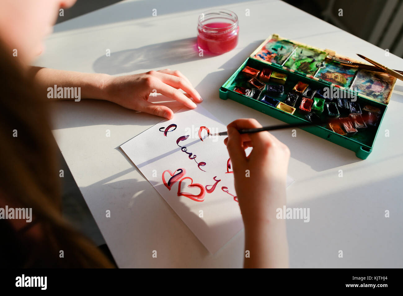 The woman artist in italics writes italic inscription on paper s Stock Photo