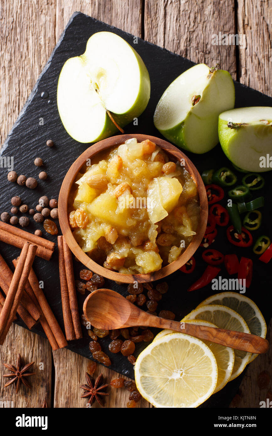 Spicy Indian sauce apple chutney with lemon closeup in a bowl on the table. Vertical top view