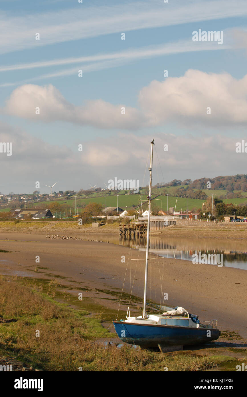 A scenic view of the Taw river estuary, Barnstaple, UK, in portrait orientation at low tide with a blue yacht in the foreground. Stock Photo