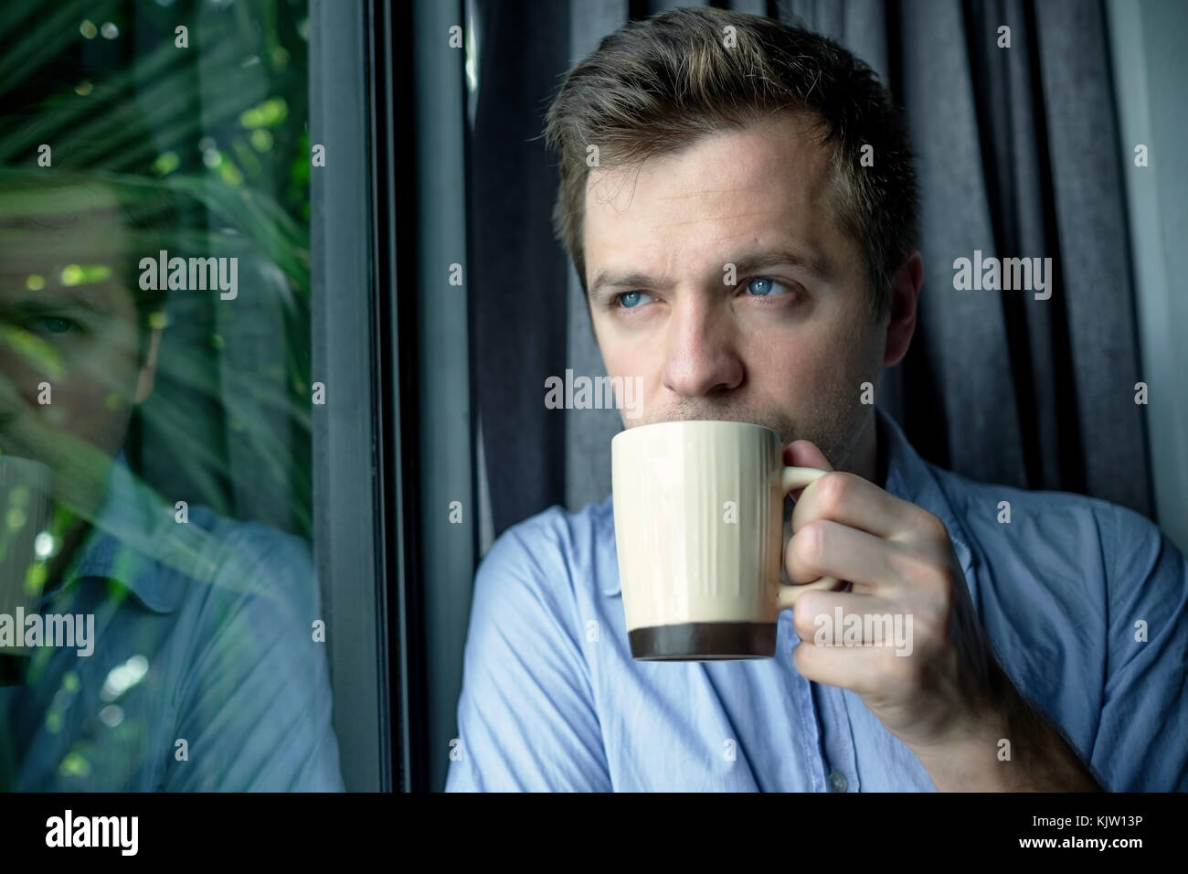 Close up portrait of businessman drinking coffee. man looking trough window and holding cup Stock Photo
