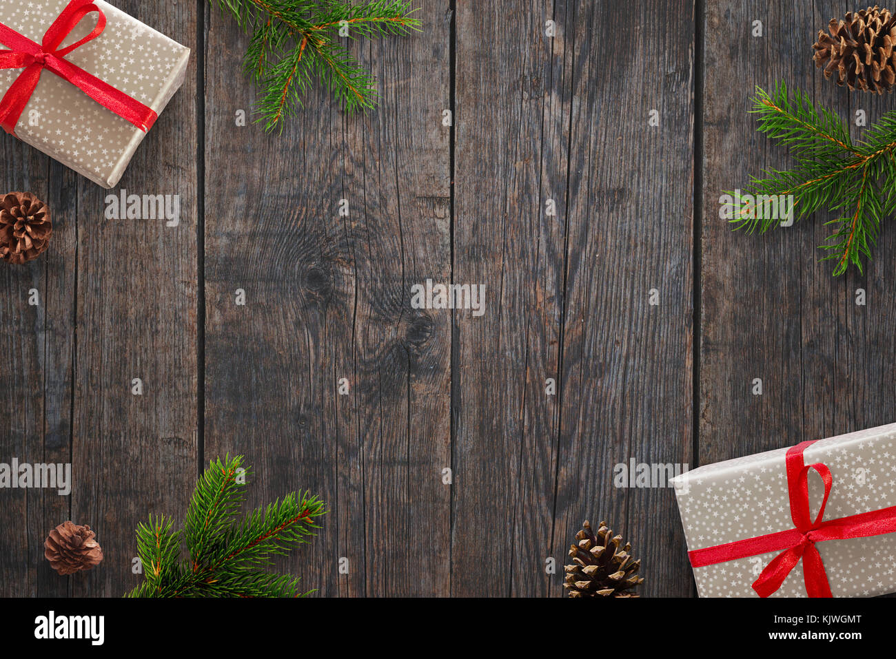 Christmas background with gifts, fir branches and pinecones over black wooden table. Top view. Stock Photo