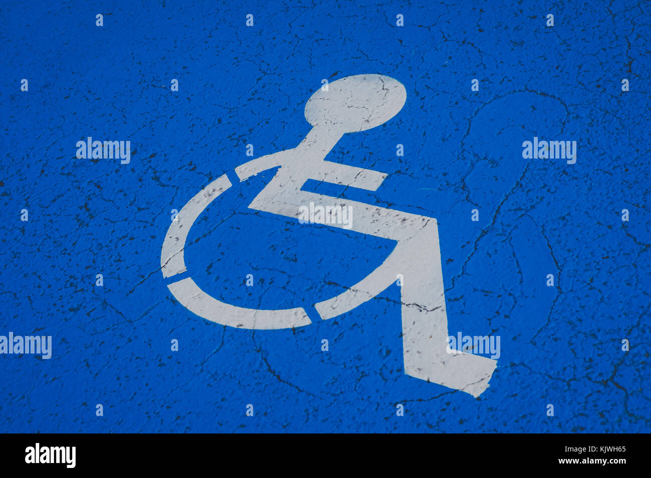 handicapped parking spot symbol - white wheelchair  on blue background - Stock Photo