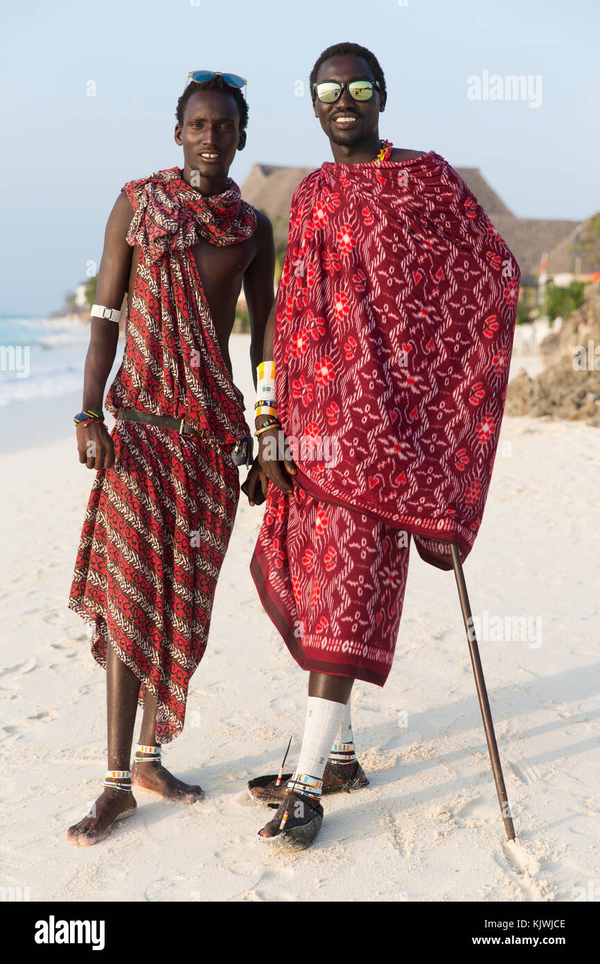 Zanzibar, Tanzania; Young Maasai warriors on the beach to sell Maasai jewelery and traditional crafts from their stalls nearby to tourists at beach hotels in the north of the island. Stock Photo