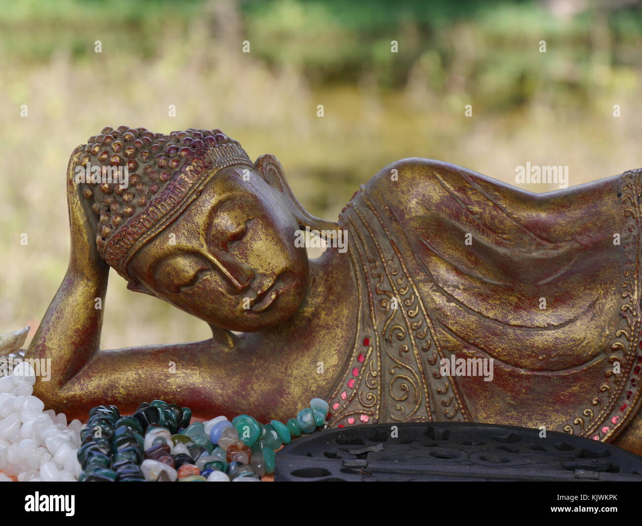 Close up of graceful reclining golden Buddha figure with expression of serenity Stock Photo